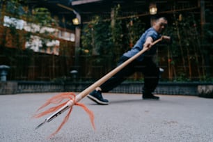a man holding a stick with an orange feather on it
