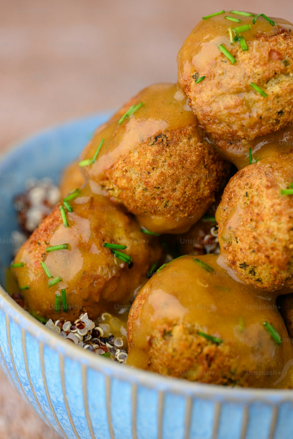 a blue bowl filled with meatballs covered in gravy
