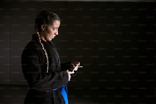 a woman standing in a dark room holding a cigarette