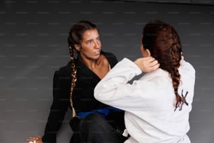 a woman is helping another woman with her karate moves