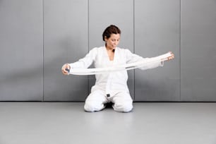 a woman sitting on the floor holding a white ribbon