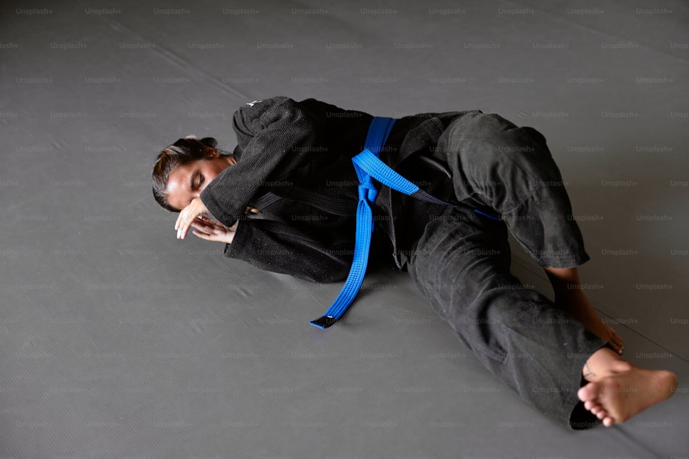 a man laying on the ground with a blue belt around his neck
