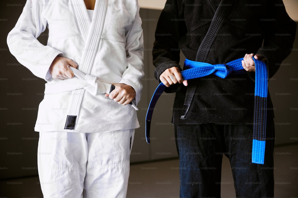 two people standing next to each other holding a blue belt