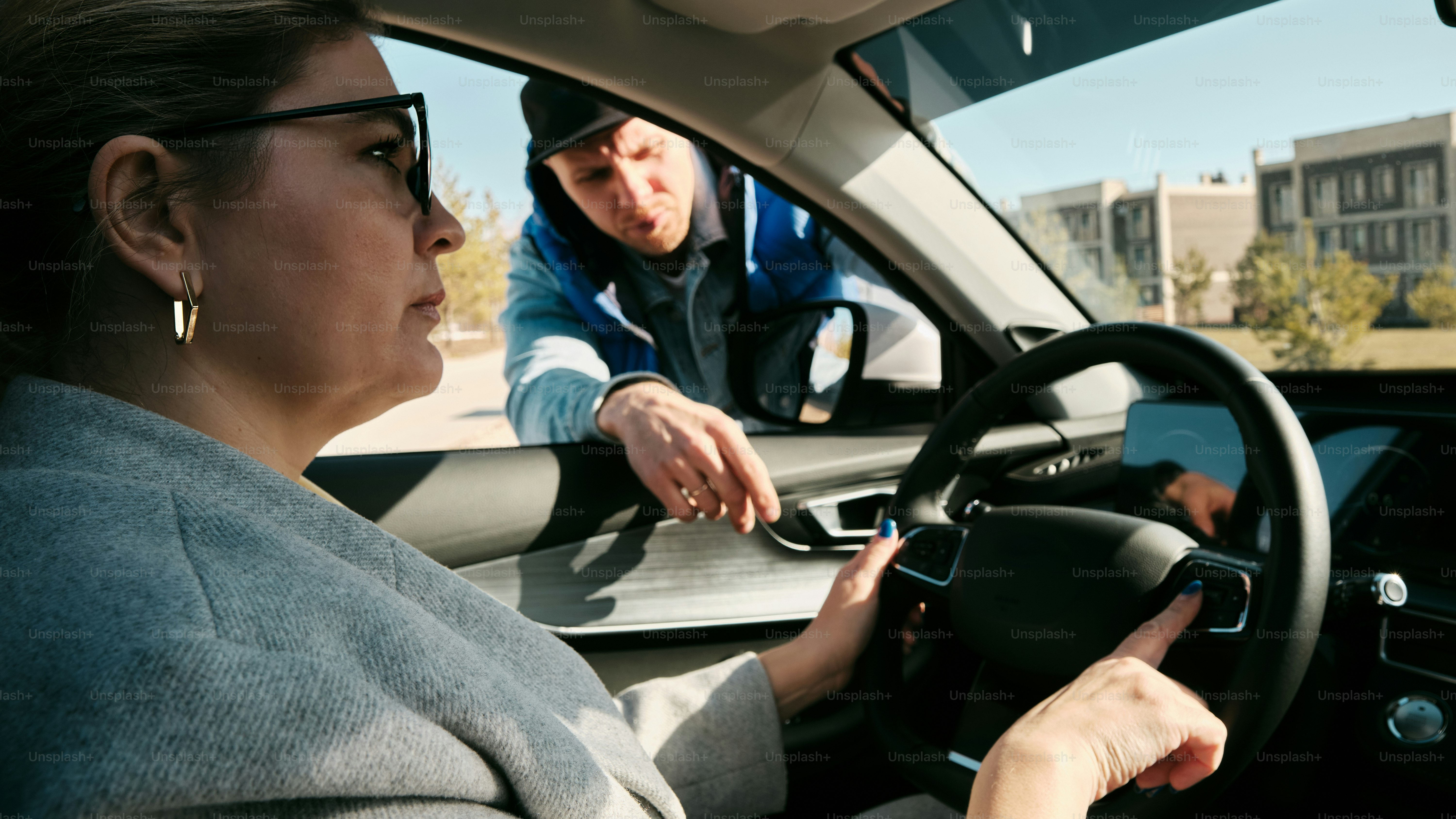 a woman driving a car with a man behind her