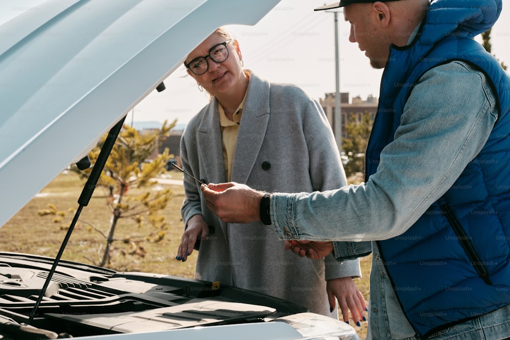 a man and a woman looking under the hood of a car