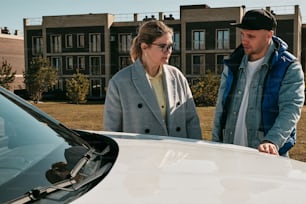 a man and a woman standing next to a white car