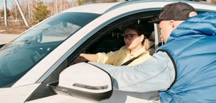 a man sitting in a car talking to another man