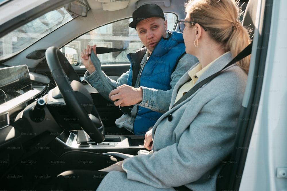 a man and a woman sitting in the driver's seat of a car