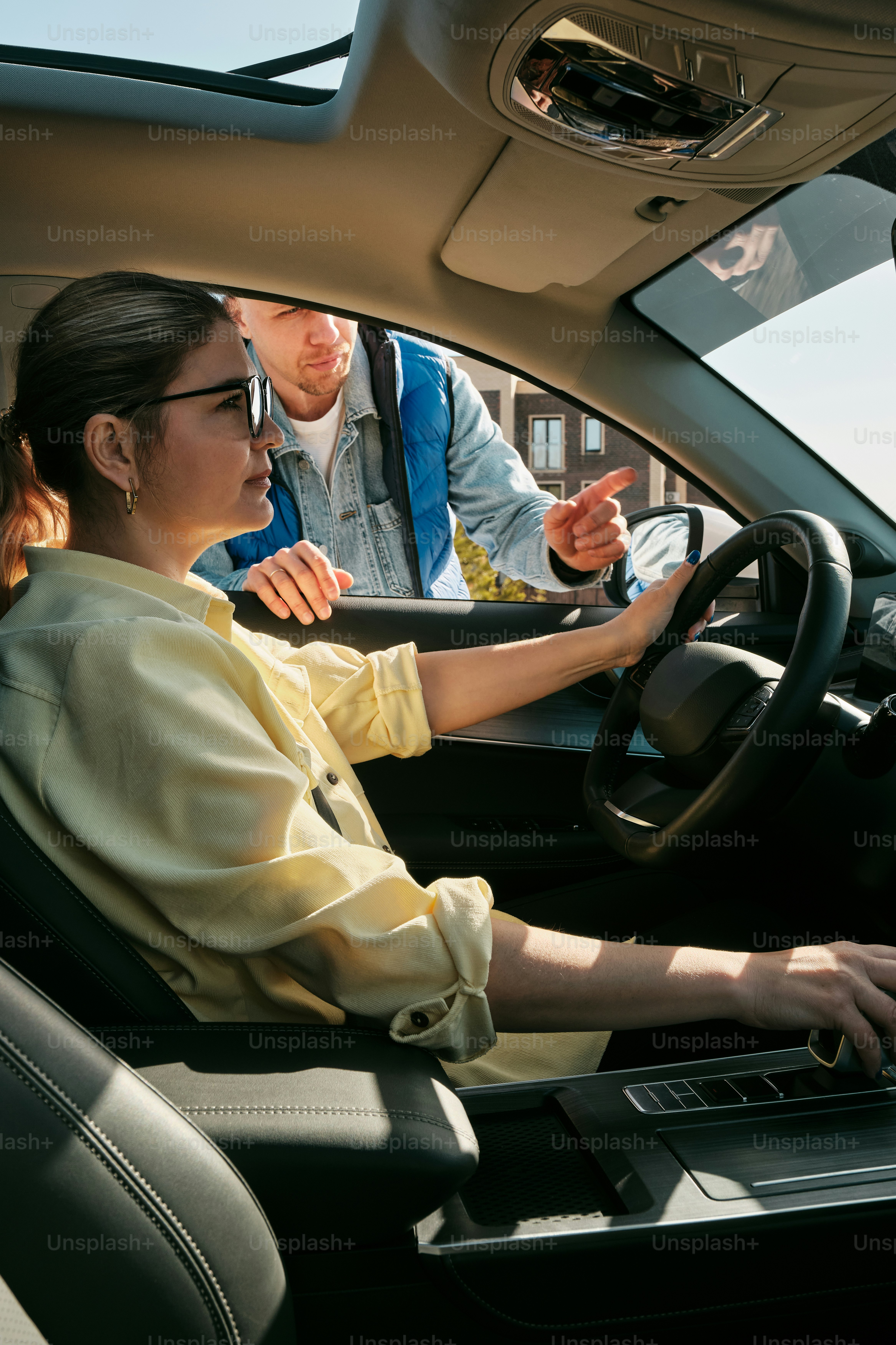 a woman driving a car with a man behind her