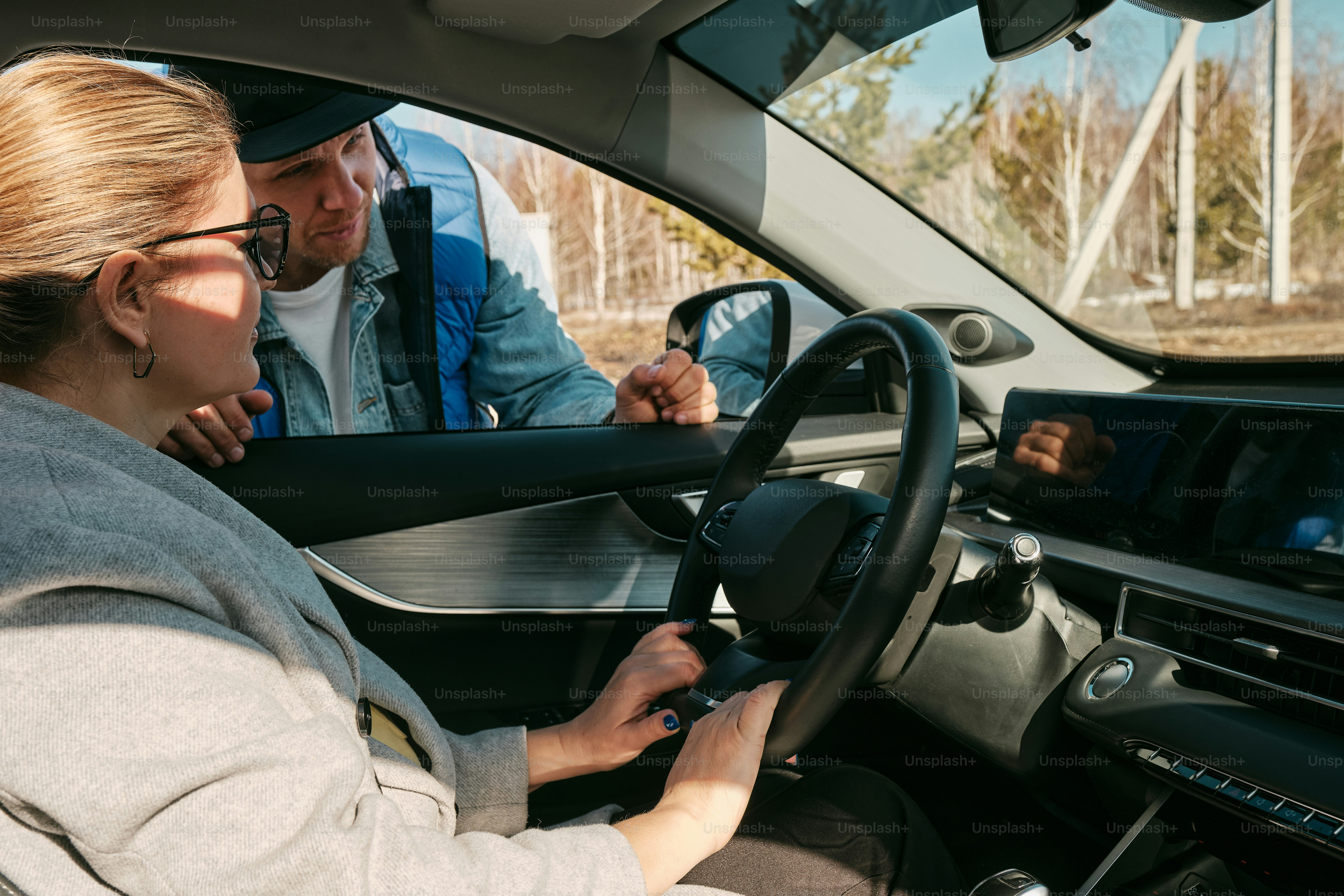 eine Frau, die ein Auto mit einem Mann hinter sich fährt
