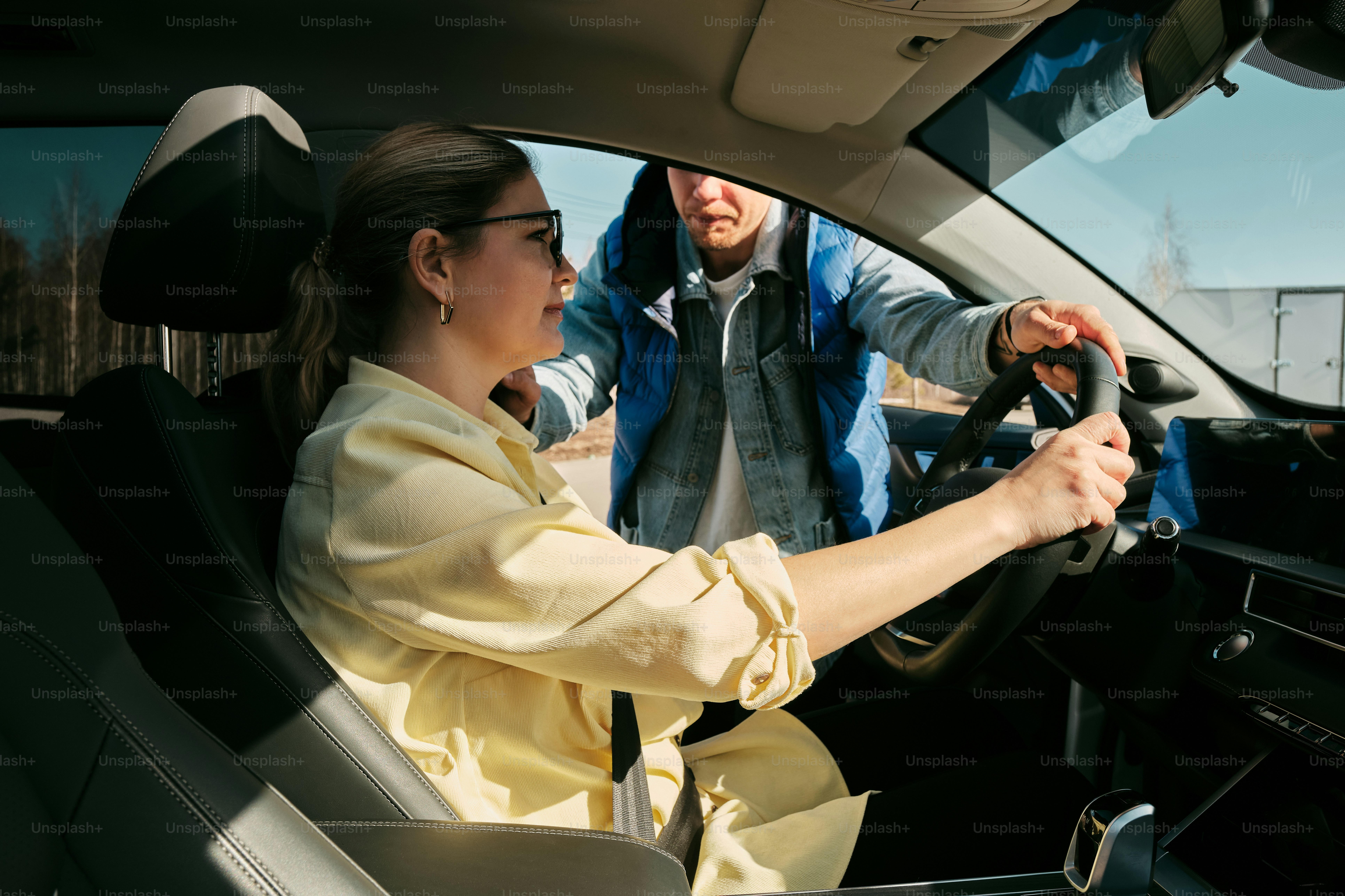 a woman driving a car with a man behind her