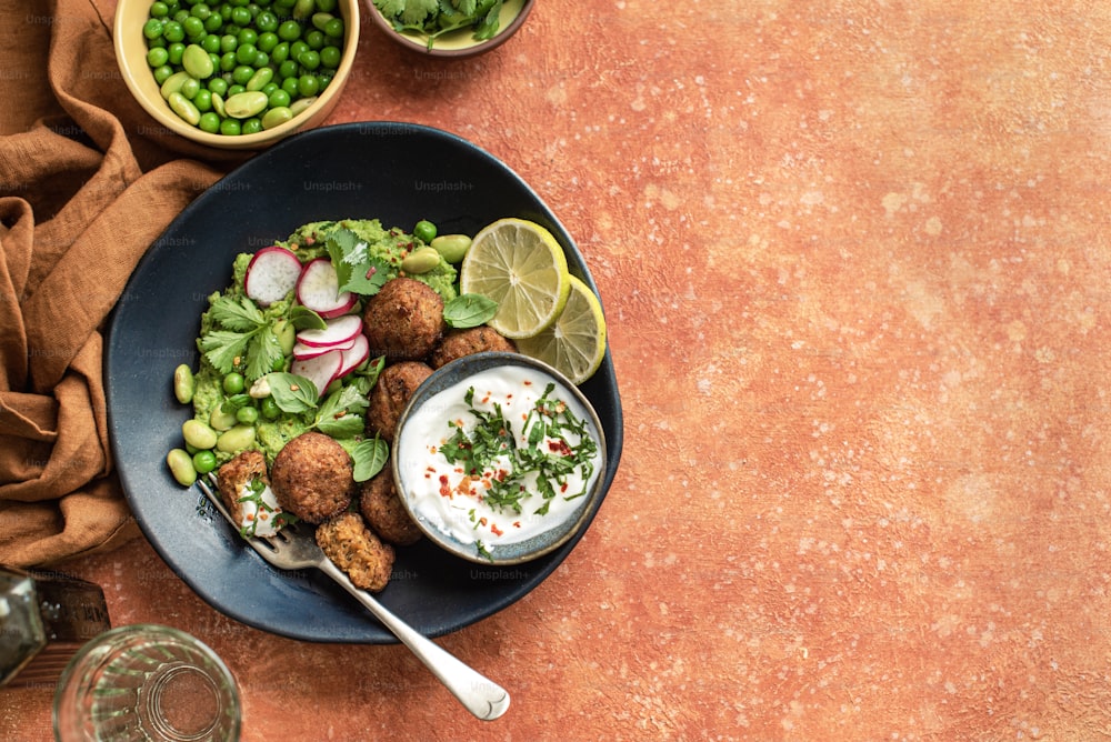 a plate of food on a table next to bowls of peas and peas