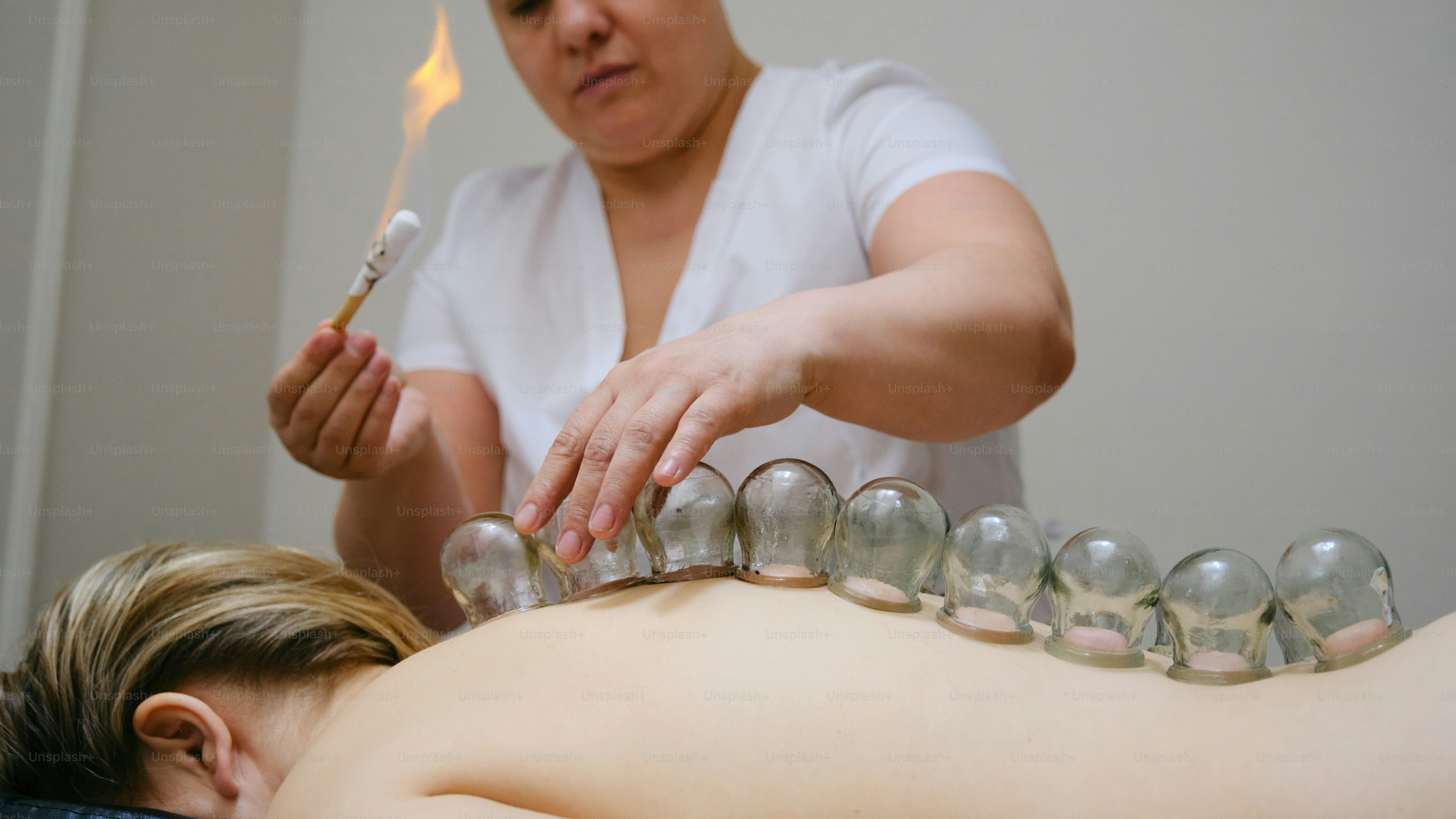 Eine Frau bekommt eine Rückenmassage mit einem Feuerzeug