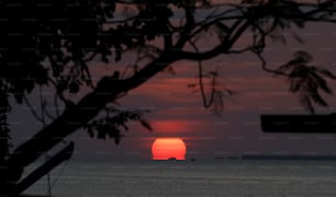 the sun is setting over the ocean with a boat in the distance