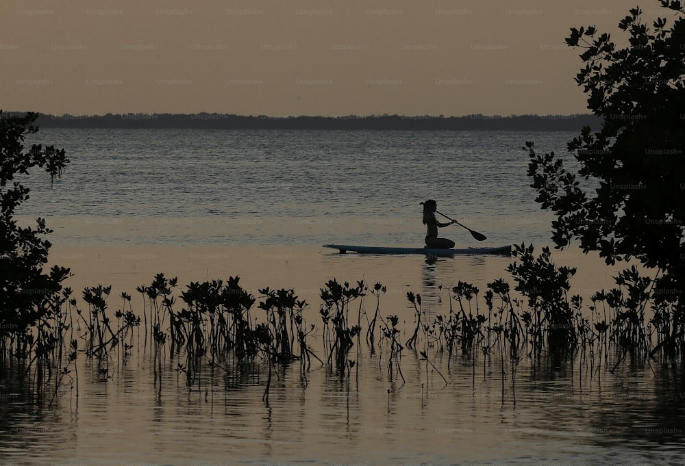 Eine Person, die bei Sonnenuntergang mit einem Kajak auf einem See paddelt