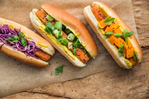 Drei Hot Dogs mit unterschiedlichen Toppings auf einem Blatt Papier