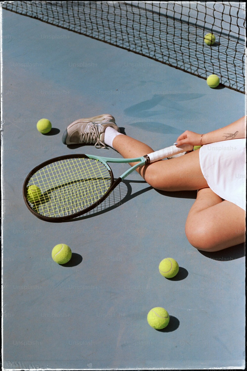 a woman sitting on a tennis court holding a tennis racquet