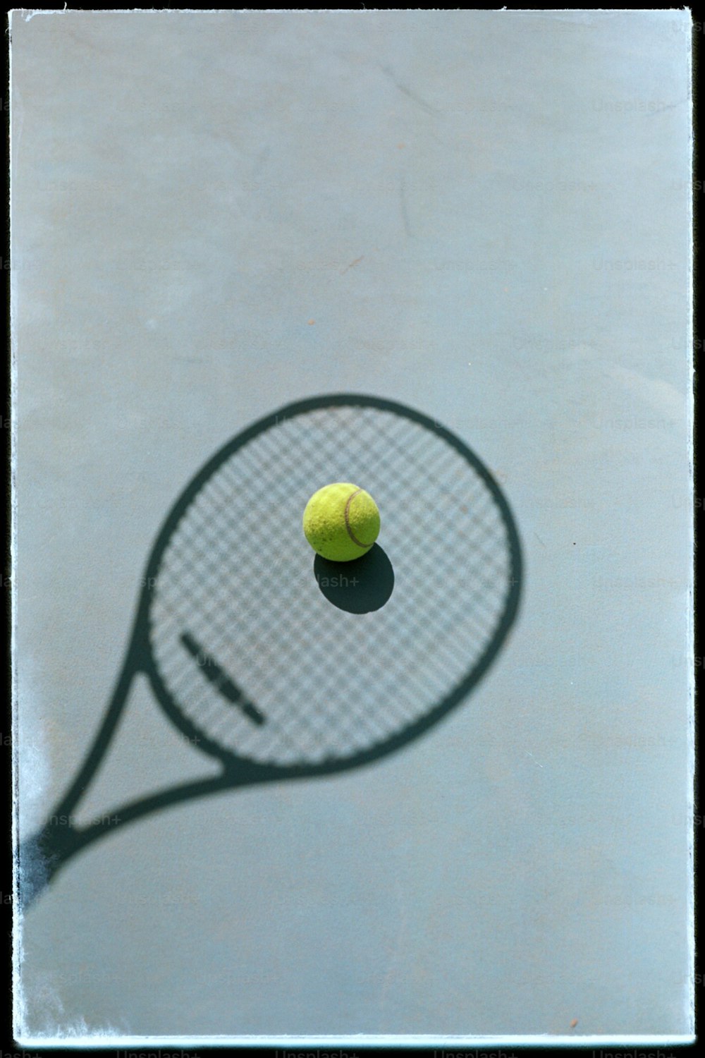 a shadow of a tennis racket and a tennis ball