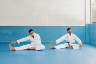 two young men sitting on the ground in karate uniforms