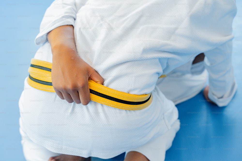 a woman in a white outfit holding a yellow belt