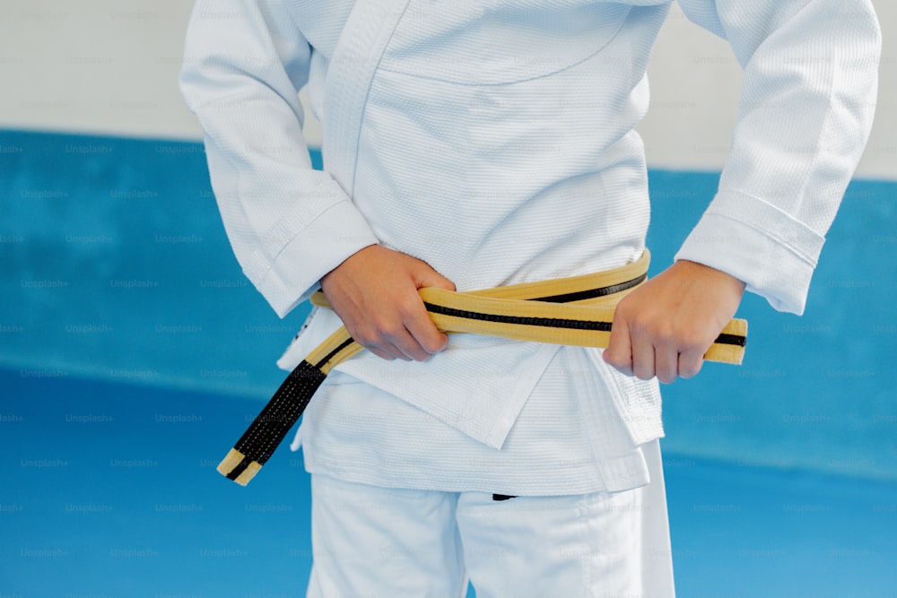 a person in a white uniform holding a yellow belt