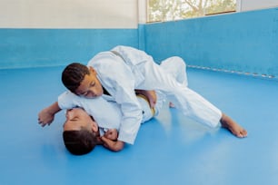 two men in white uniforms are fighting on a blue mat