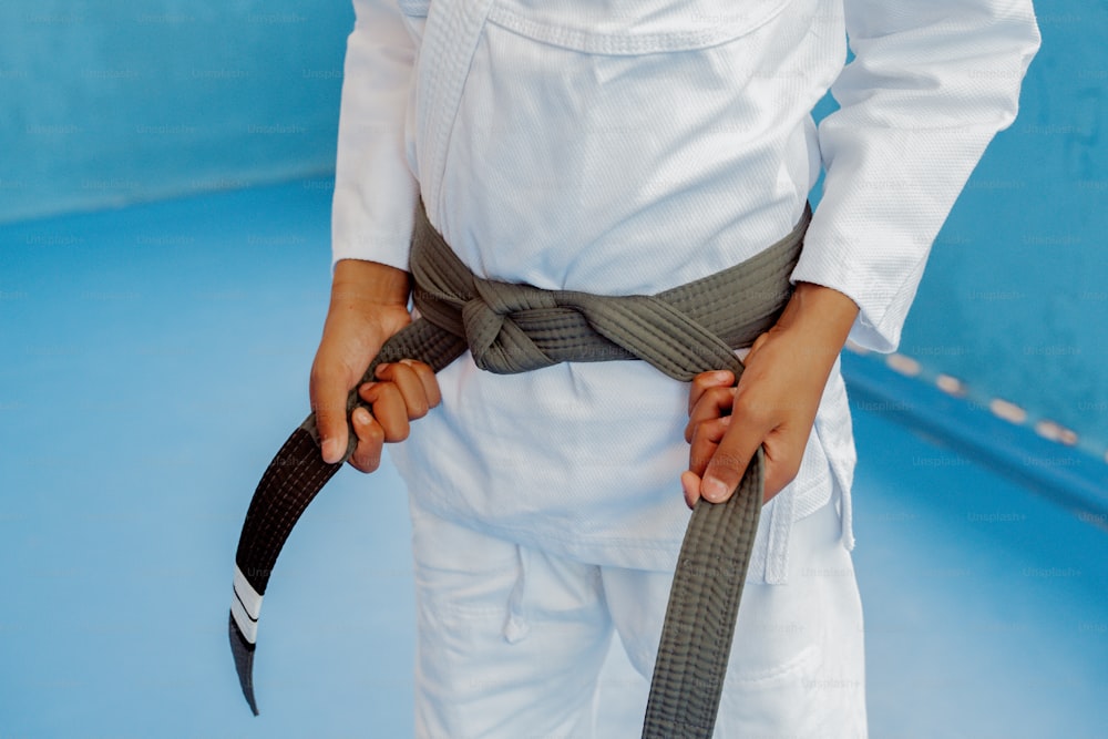 a person wearing a white suit holding a black belt