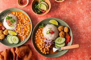 two plates of food with rice, beans and cucumbers