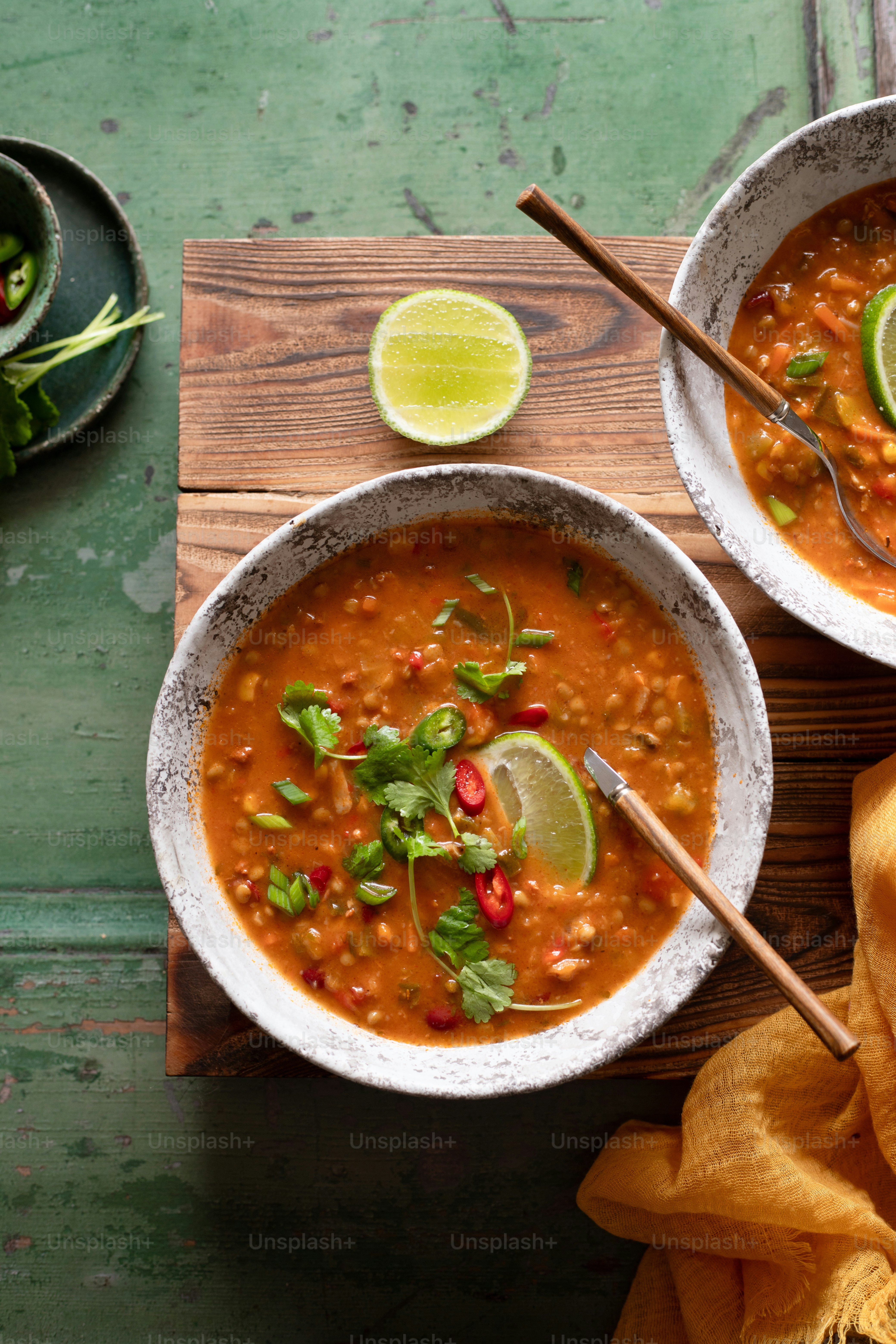 two bowls of chili soup with limes and cilantro