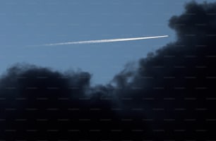 a jet flying through a blue sky with clouds