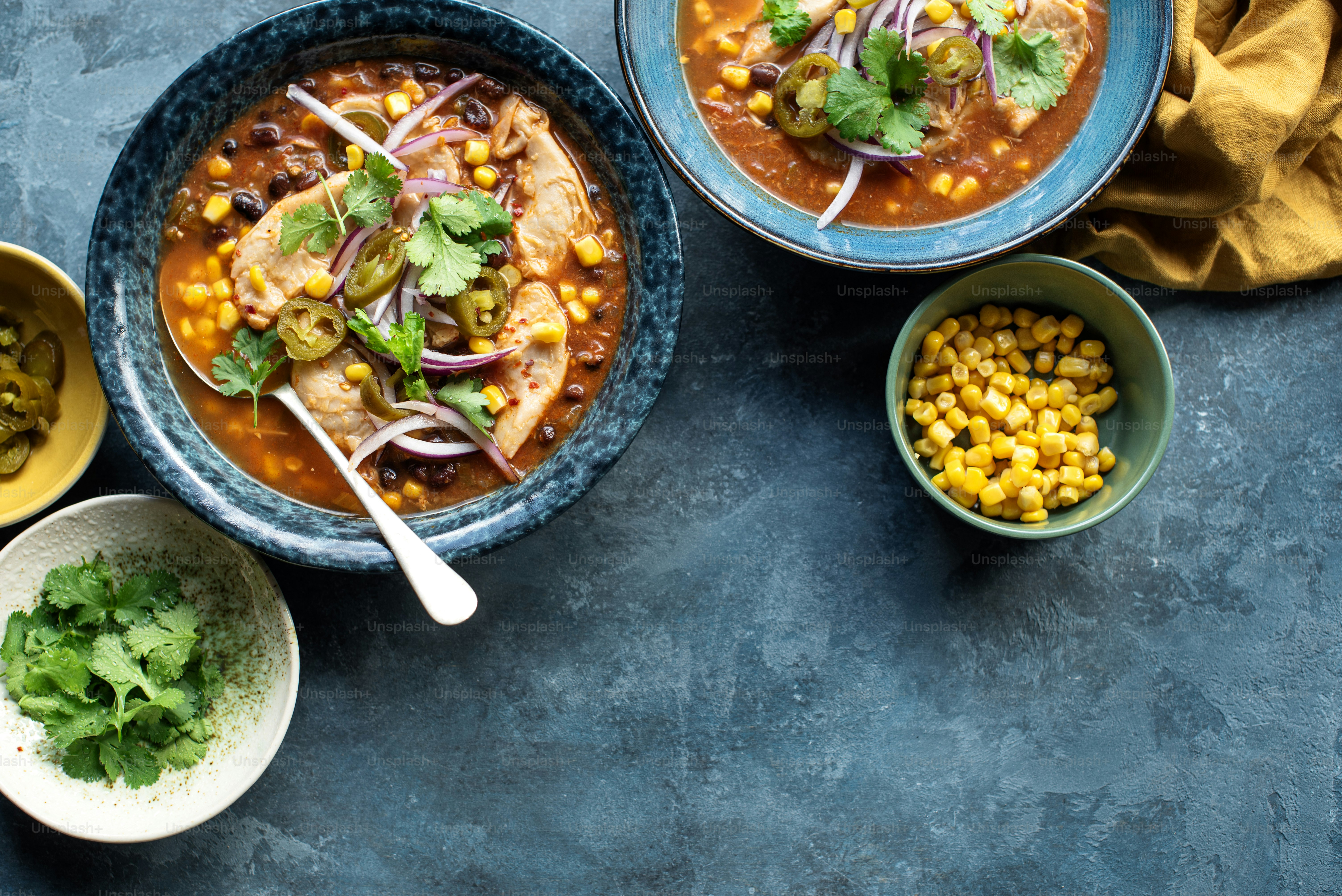 a table topped with bowls of soup and bowls of vegetables