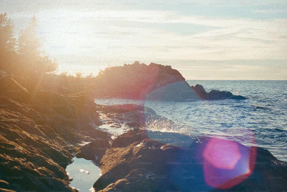 the sun shines brightly on a rocky shoreline