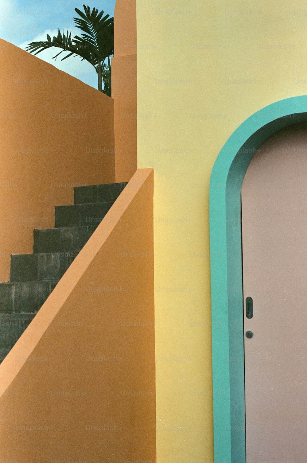 une porte rose, des escaliers et un palmier