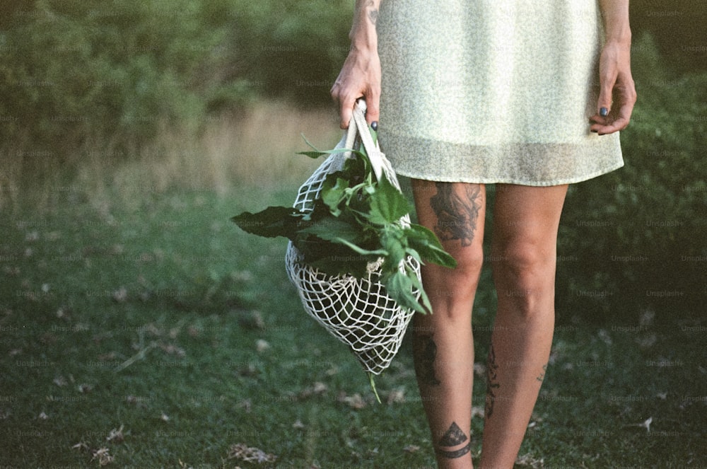 a woman in a white dress holding a bag of flowers