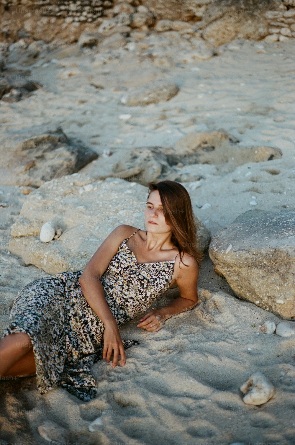 una donna sdraiata su una spiaggia vicino a una roccia