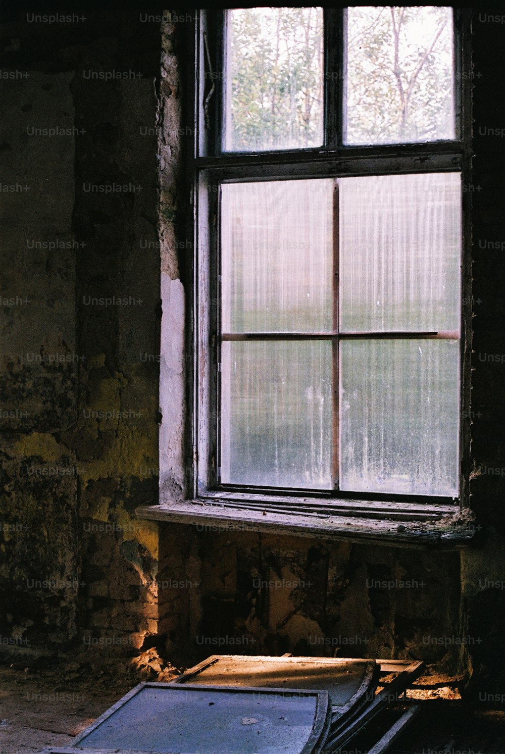 a window in a run down building with a broken pane of glass