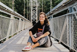 a woman is sitting on a bridge and smiling