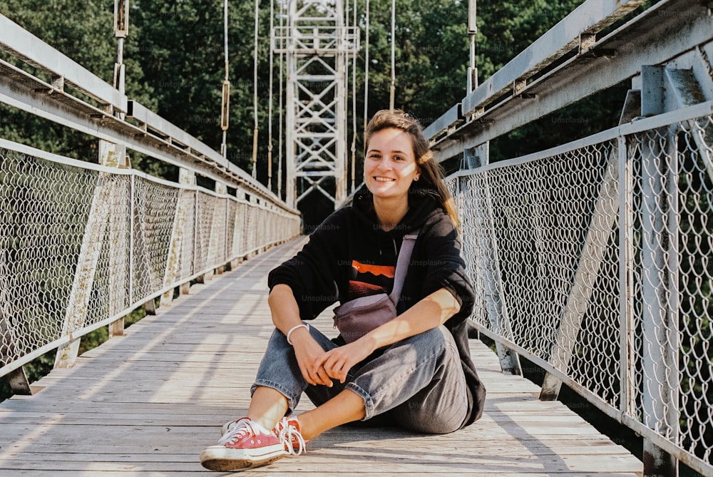 a woman is sitting on a bridge and smiling