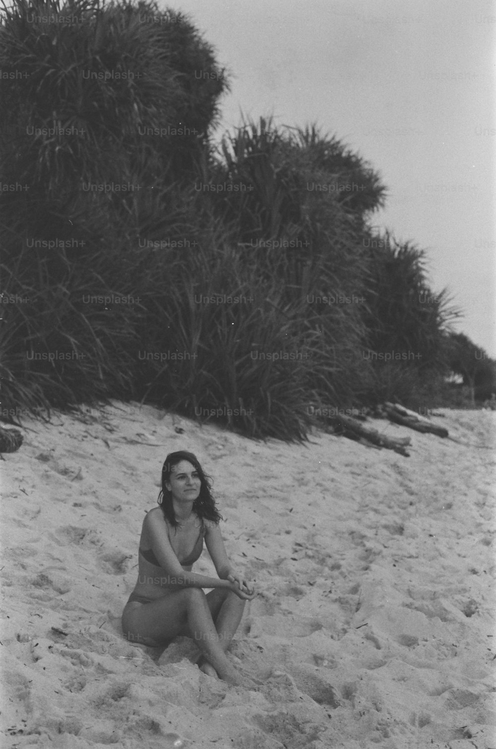 uma mulher sentada na areia em uma praia