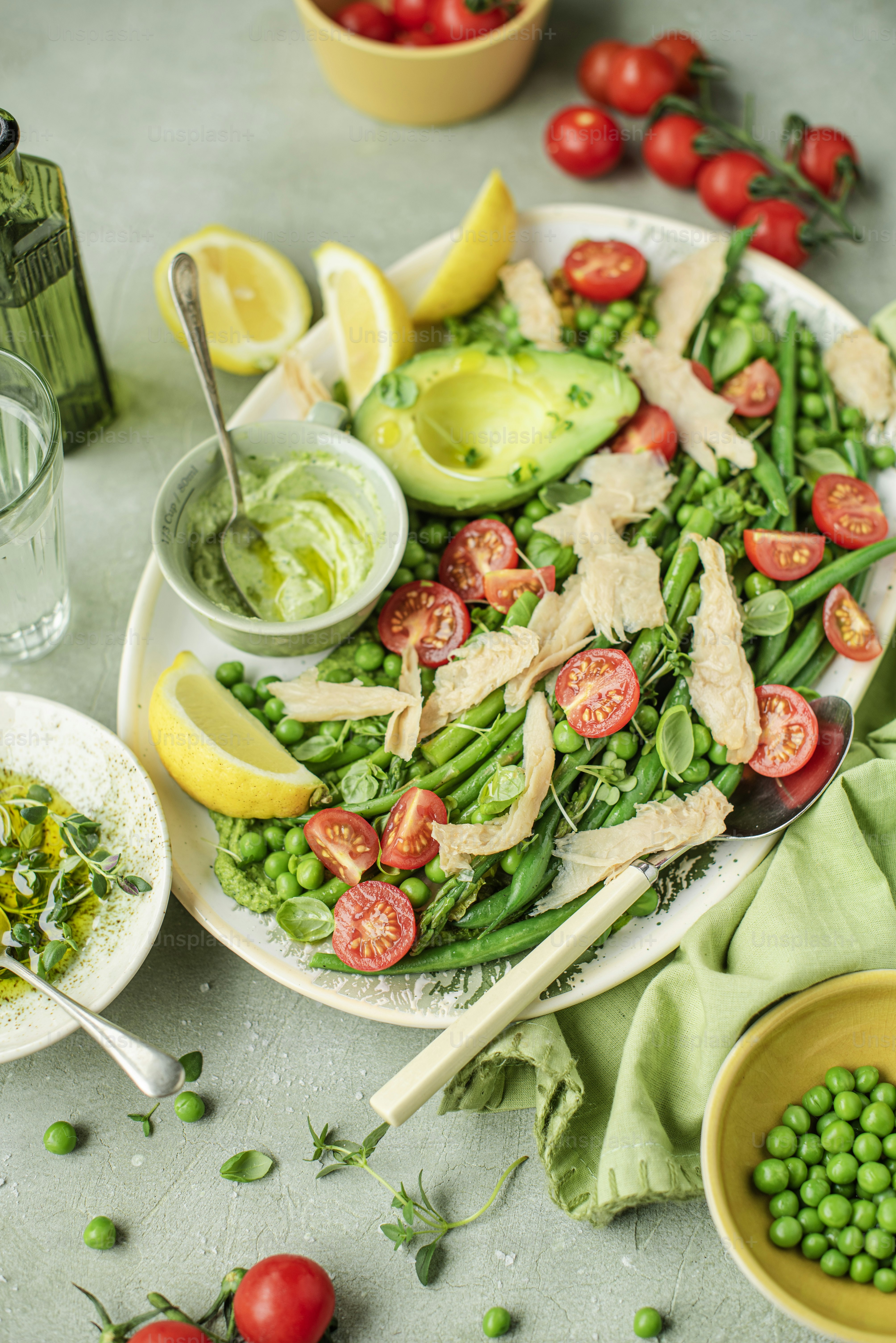 a plate of green beans, peas, tomatoes, and avocado