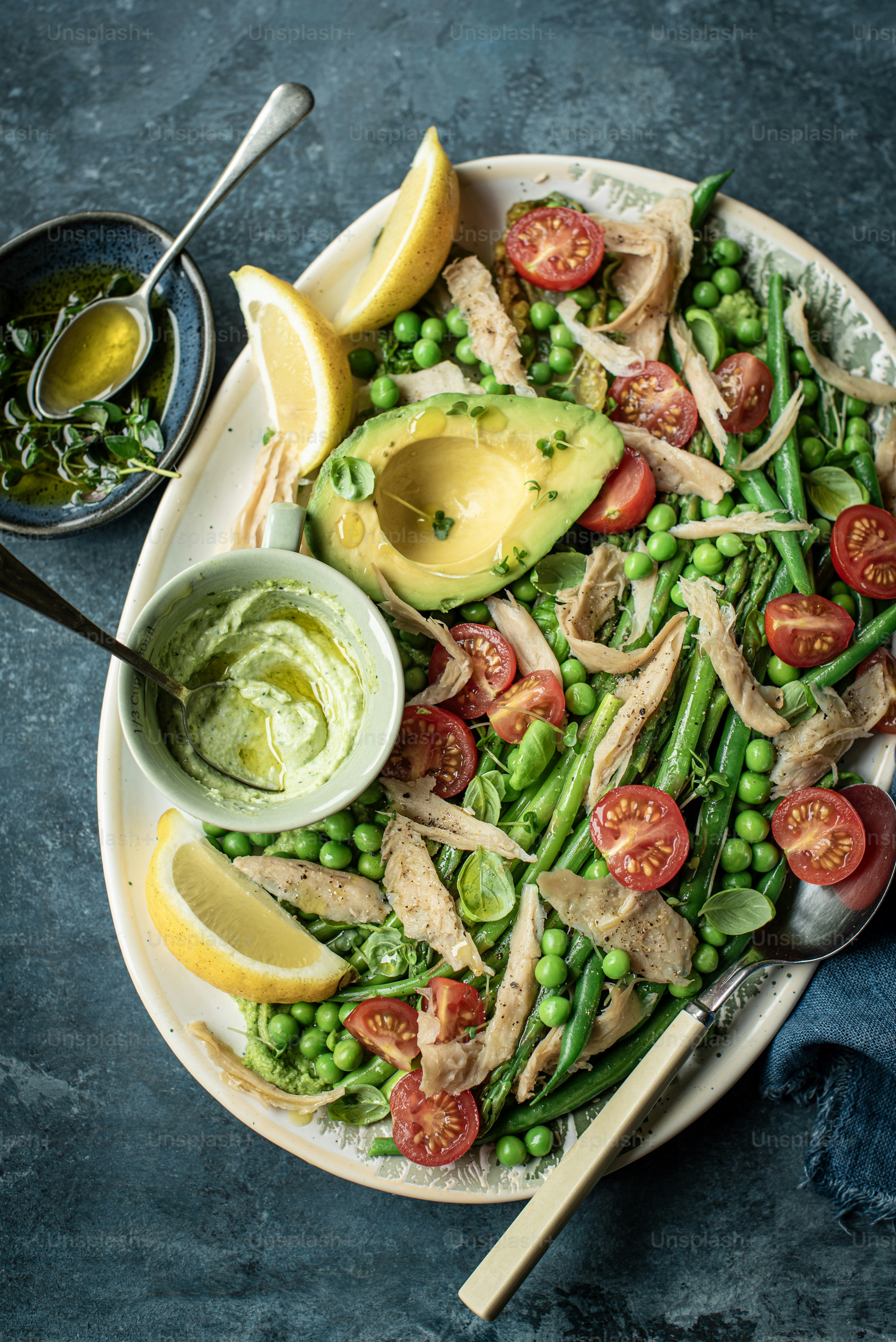 a plate of food with peas, tomatoes, avocado and chicken