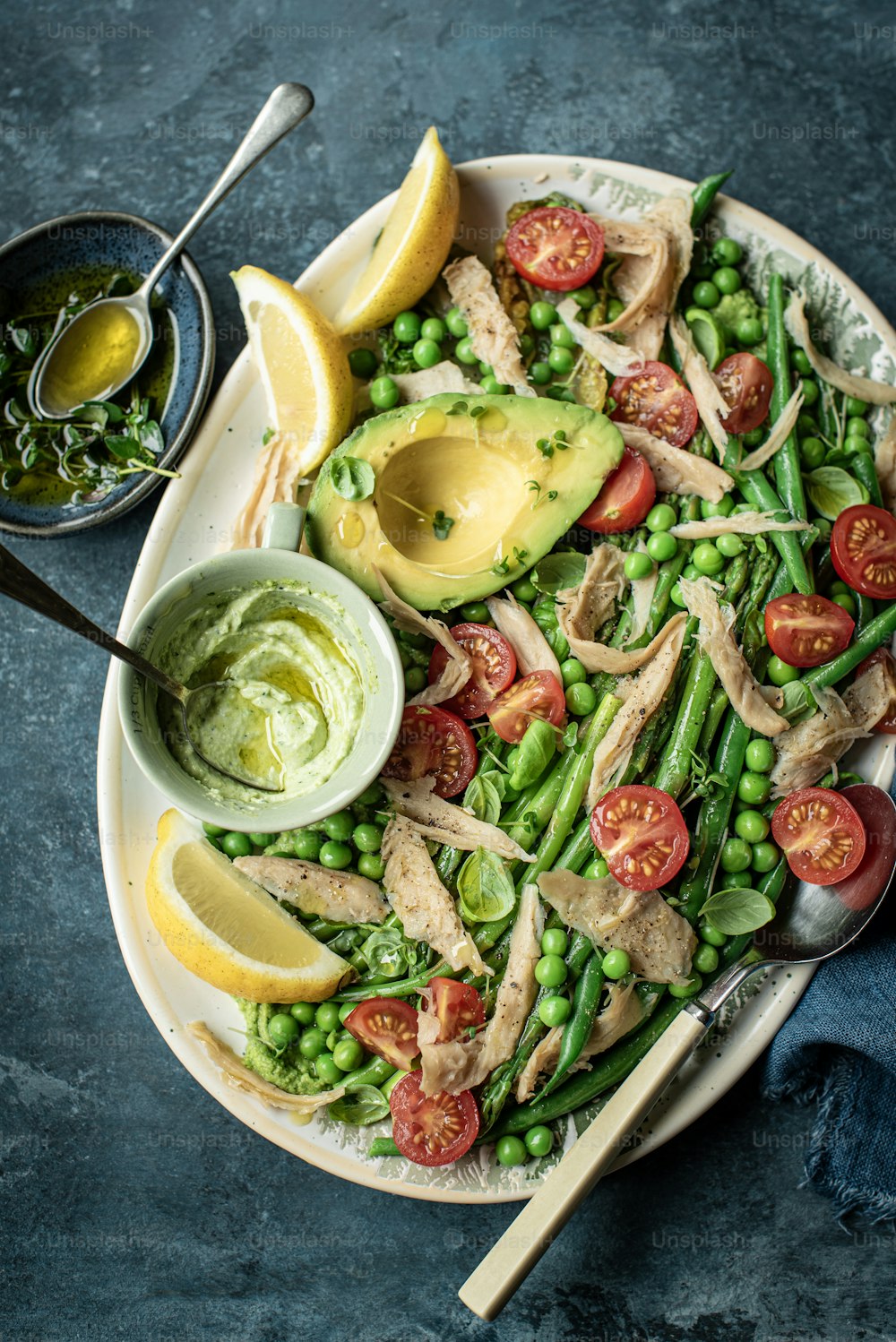 a plate of food with peas, tomatoes, avocado and chicken