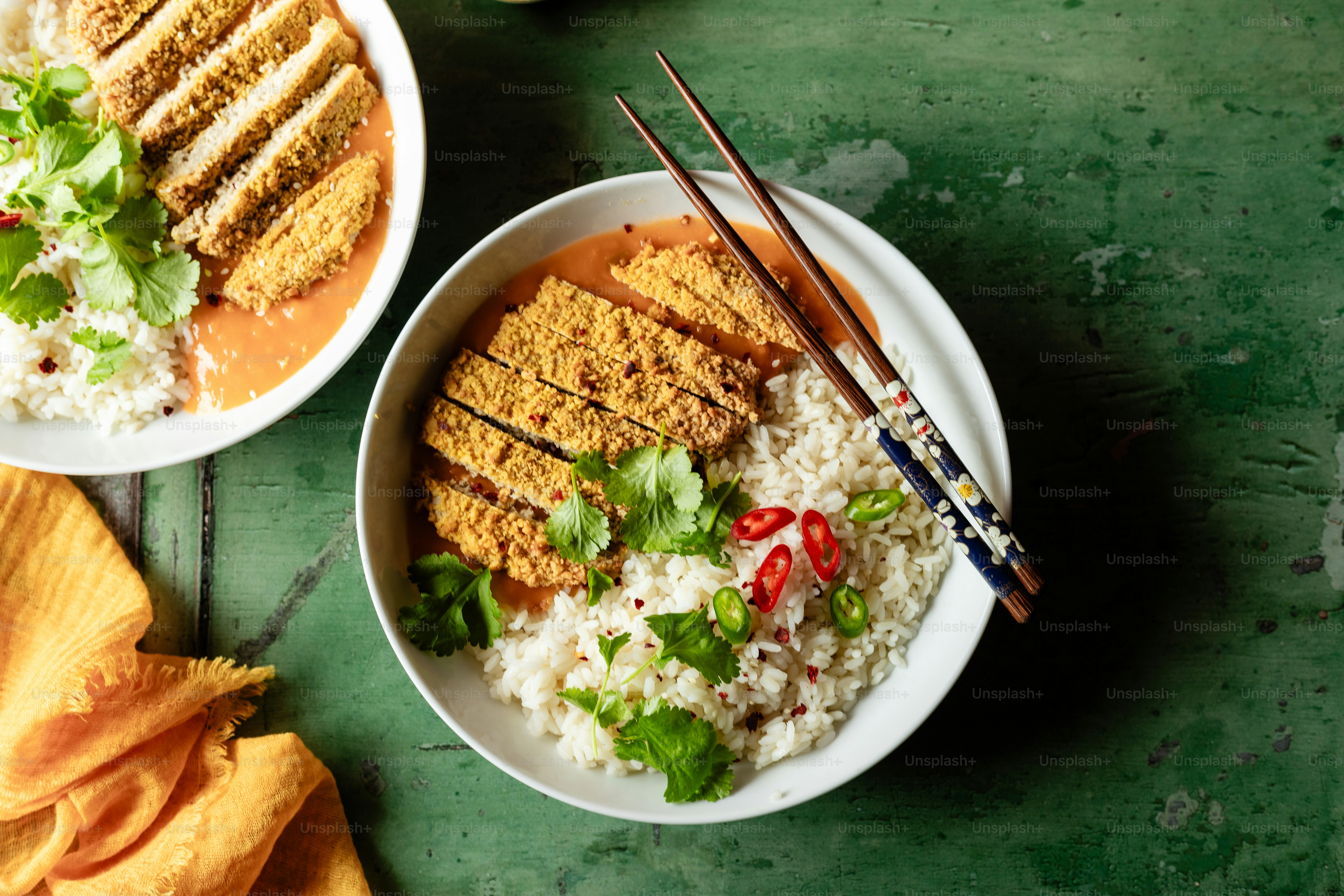 Two plates of food on a table with chopsticks photo – Rice Image on ...
