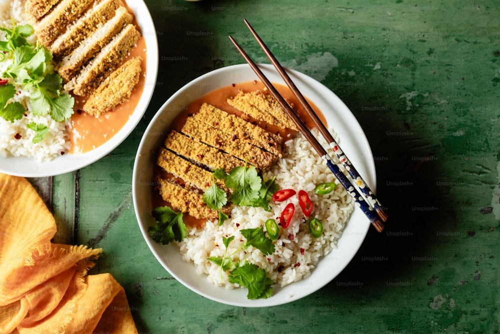 two bowls of food on a table with chopsticks