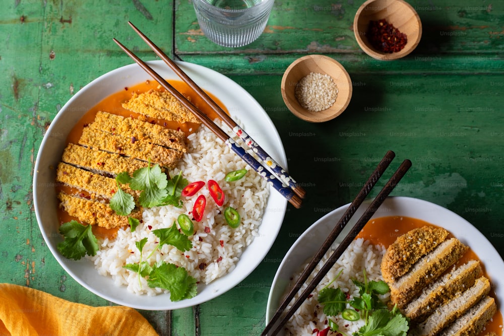 Dos platos de comida con palillos y arroz