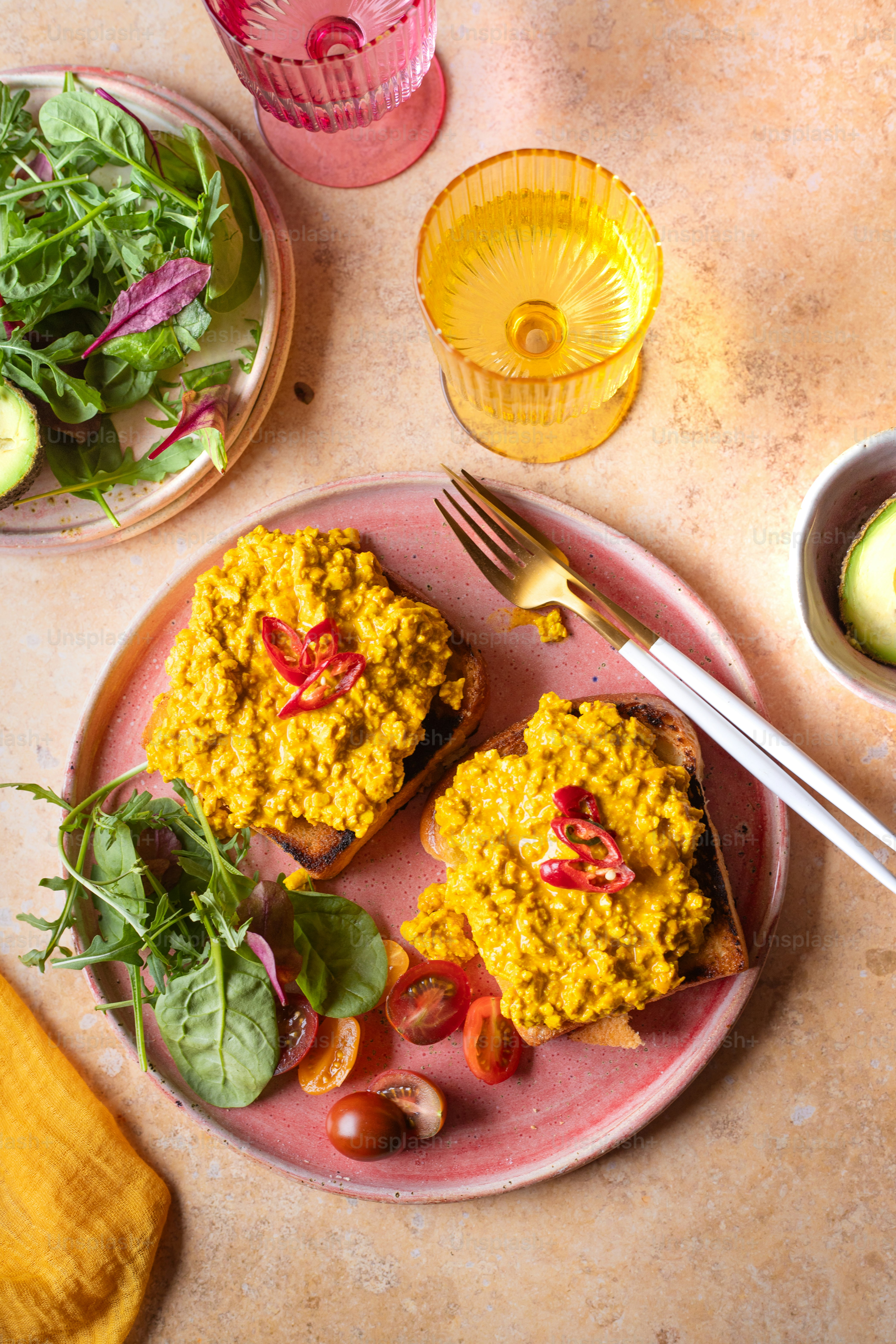 サラダのボウルの隣に食べ物をトッピングしたピンクのプレート