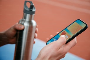 a person holding a cell phone next to a water bottle