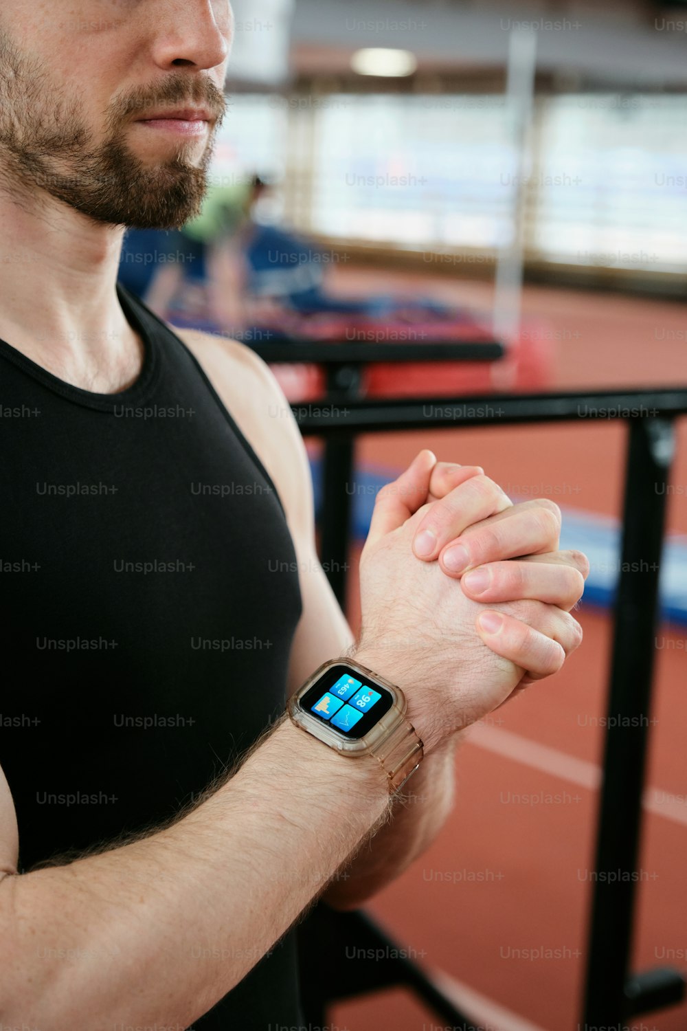 a man in a black tank top holding a smart watch