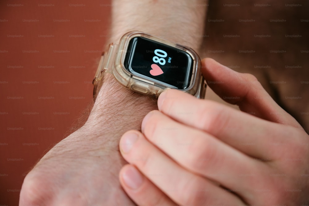 a man holding a smart watch with a heart on it