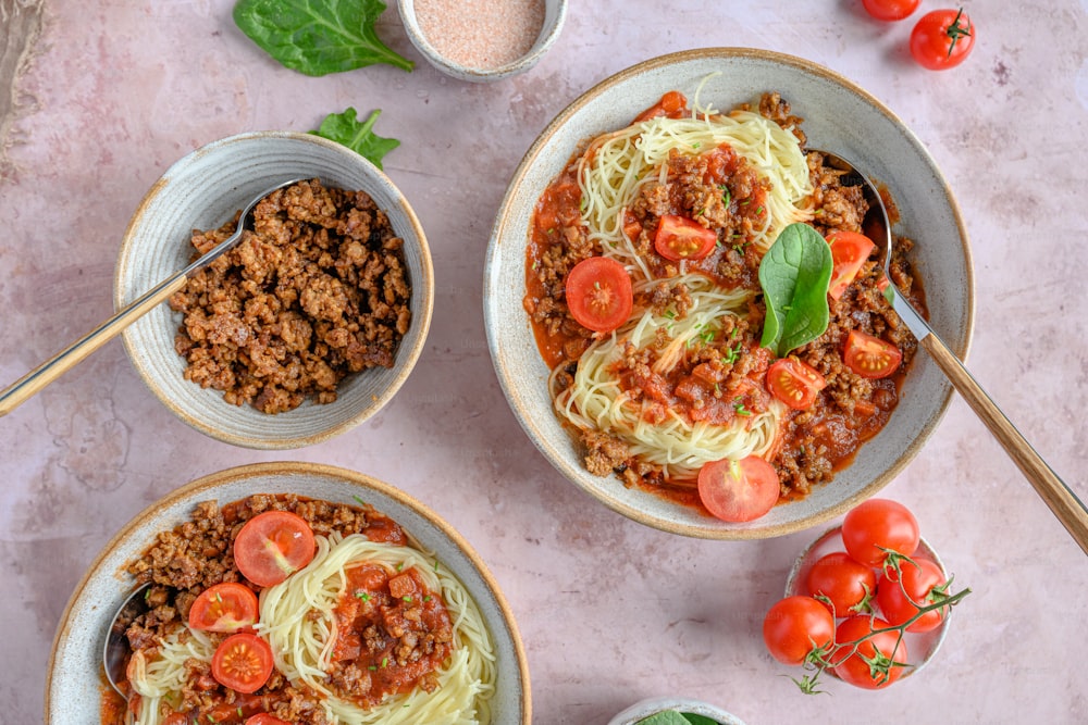three bowls of spaghetti with meat and tomatoes